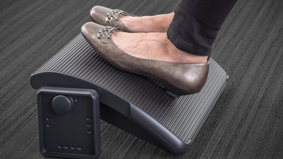 Detalle de reposapiés ergonómico colocado bajo un escritorio de trabajo