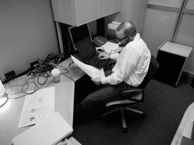 Man on the phone at a crowded desk with exposed cables