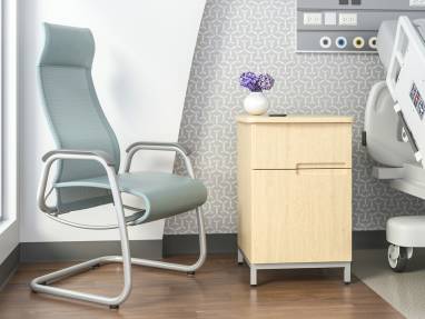 Green high-back Cura patient chair in the corner of a recovery room in front of a window