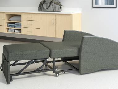 A dark grey Mitra Sleeper fully extended to bed form ina medical room