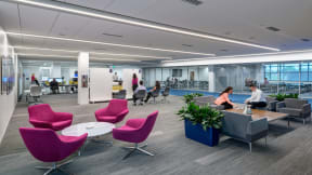 People collaborating on a open area with different products such as whiteboards, grey lounges, Node chairs.