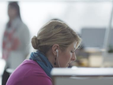 Woman with earbuds in an office
