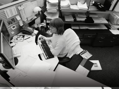 Woman sitting at an unorganzied desk without Universal Storage