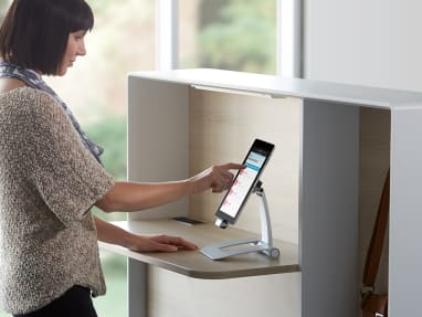 Woman standing using a tablet mounted on the Regard booth cabinet