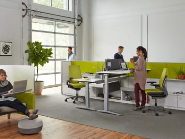 Two Series 5 height-adjustable desks in an open office next to a lounge area
