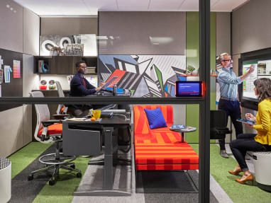 Three people work together in an office enclave furnished with Turnstone Buoy seating, Steelcase Think stools, and a Steelcase Ology bench Steelcase Room Wizard is seen next to the door