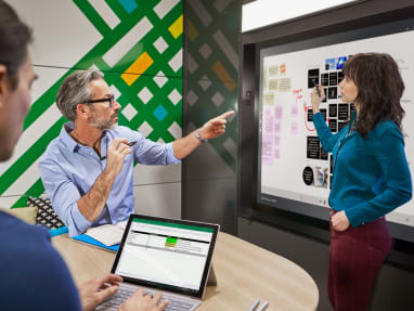 Man and woman on a private room collaborating while using an interactive ideation hub surface