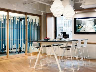 Montara650 stools are arranged around a Potrero415 table with a wall-mounted monitor nearby