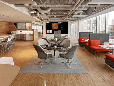 An office cafe setting features gray SW_1 lounge chairs, Lagunitas lounge seating with orange upholstery, and SW_1 tables