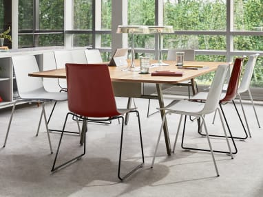 Several red and white armless Nooi chairs arranged around a table