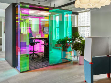 Two SILQ chairs sit around a Mackinac workstation in a multi-colored IRYS Pod