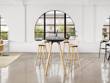 A Potrero415 Light table with wood legs and black top and Enea Cafe wood stools around it