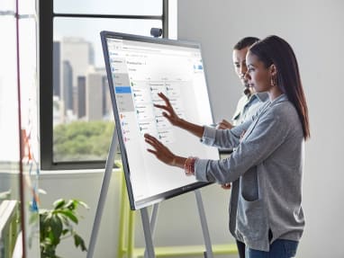 Woman touches a screen displayed on a Steelcase Roam Mobile Stand