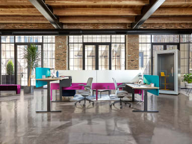 An office environment featuring Migration height-adjustable desks, Steelcase Series 1 chairs, and an Answer Fence. A SnapCab Pod with Coalesse Enea Lottus stool is seen nearby.