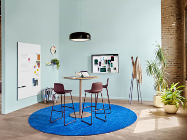 Meeting space with Coalesse Enea Lottus stools around a Montara650 table. A Blu Dot Splash coat rack and PolyVision Sans CeramicSteel whiteboard are also seen.