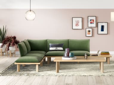 A West Elm Work Boardwalk lounge sofa with green cushions around a West Elm Work Boardwalk rectangular coffee table