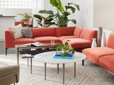 A West Elm Work Mesa sectional sofa with orange upholstery shown with West Elm Work tables in an office lounge setting