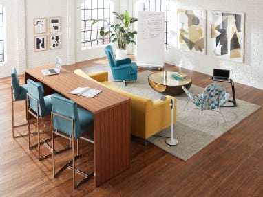 Open working sace featuring partner products including a standing height table, a colorful sofa and individual seats.