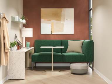 A small clinician respite space with a couch, tables, foot stool and pillow.