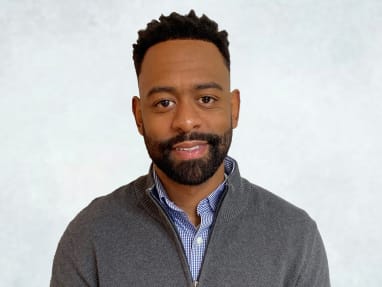 bron jones headshot wearing a gray sweater