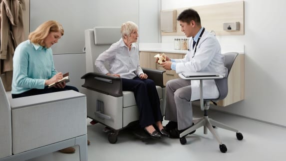 A doctor sits in a Node chair with attached Share Surface while meeting with a patient