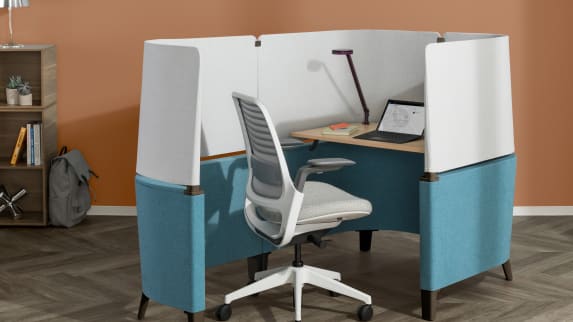A light gray Steelcase Series 1 Chair stands in front of a blue Brody Desk.