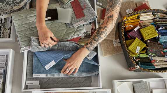 Overhead photo showing a person's arms as they look through Designtex upholstery samples
