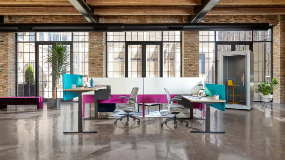 An office environment featuring Migration height-adjustable desks, Steelcase Series 1 chairs, and an Answer Fence. A SnapCab Pod with Coalesse Enea Lottus stool is seen nearby.
