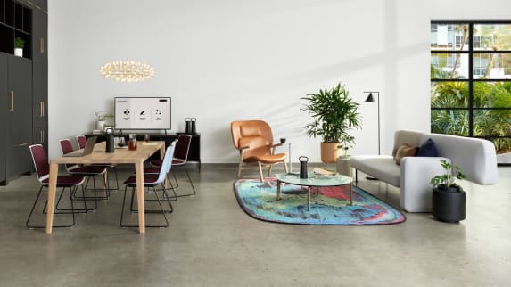 Ancillary setting with a variety of Partner products, that includes a gray Bolia Pebble Sofa, a white oak Bolia Graceful Dining Table, plum and white Nooi Seating, and a colorful Moooi rug.