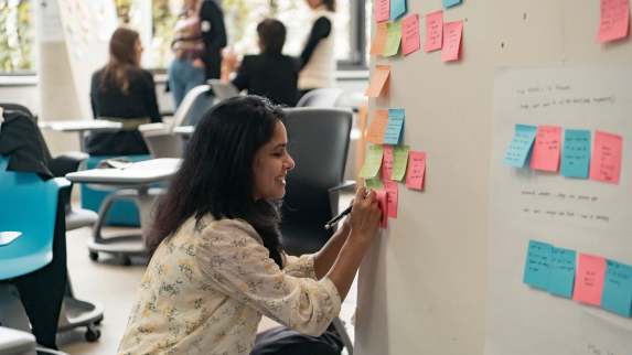 Young lady pasting post its on a bulletin board