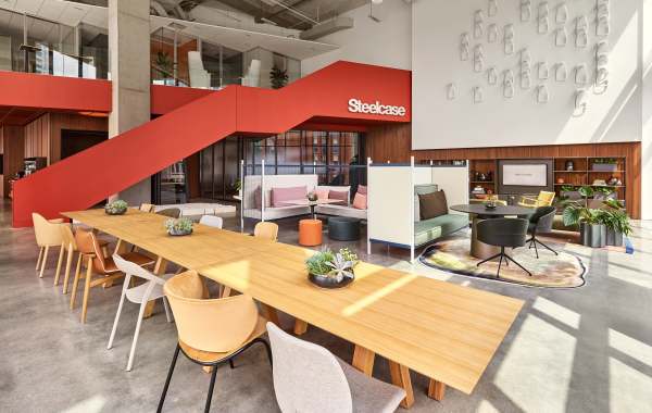 Open space with wooden table and orange staircase with steelcase logo.