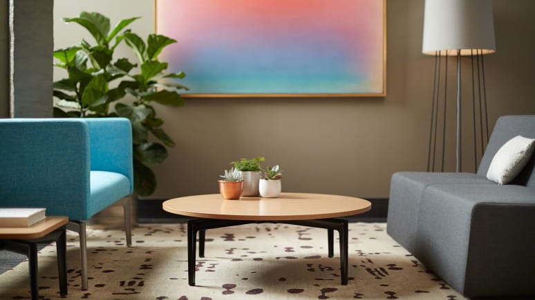 gray sofa with white pillow, round wooden table in the center, blue sofa chair