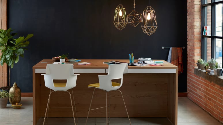 Wooden Big Table with magazines and books on it, two yellow stools with white back.