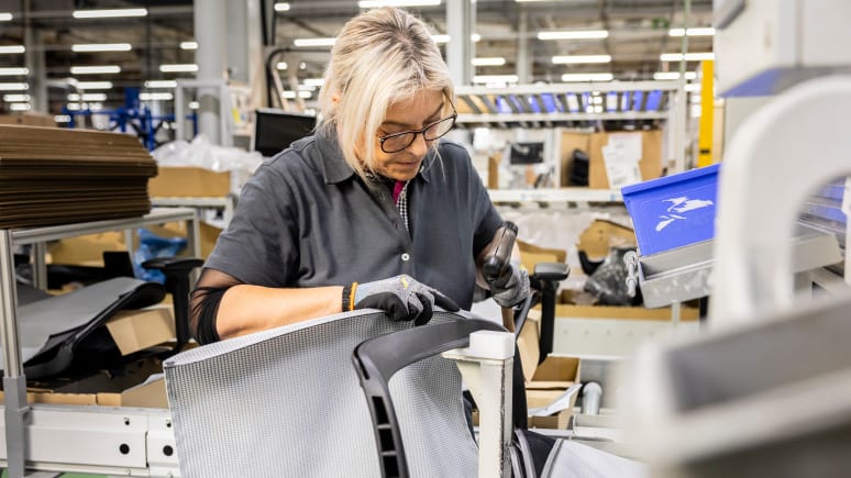 Woman reconditioning a chair in a plant environment.