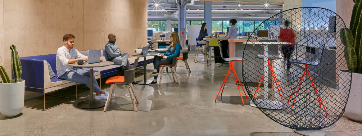 People work in an office lounge while using Umami lounge seating and Shortcut Wood chairs. Viccarbe Klip stools are also pictured.