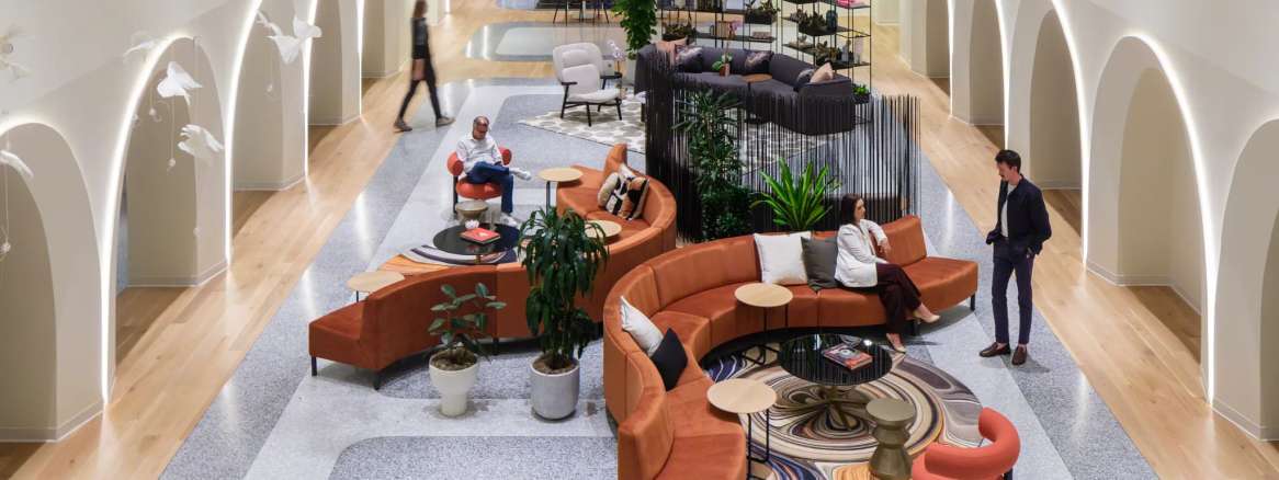 Espacios colaborativos y zonas de descanso con mobiliario de oficina moderno y elementos decorativos naturales.