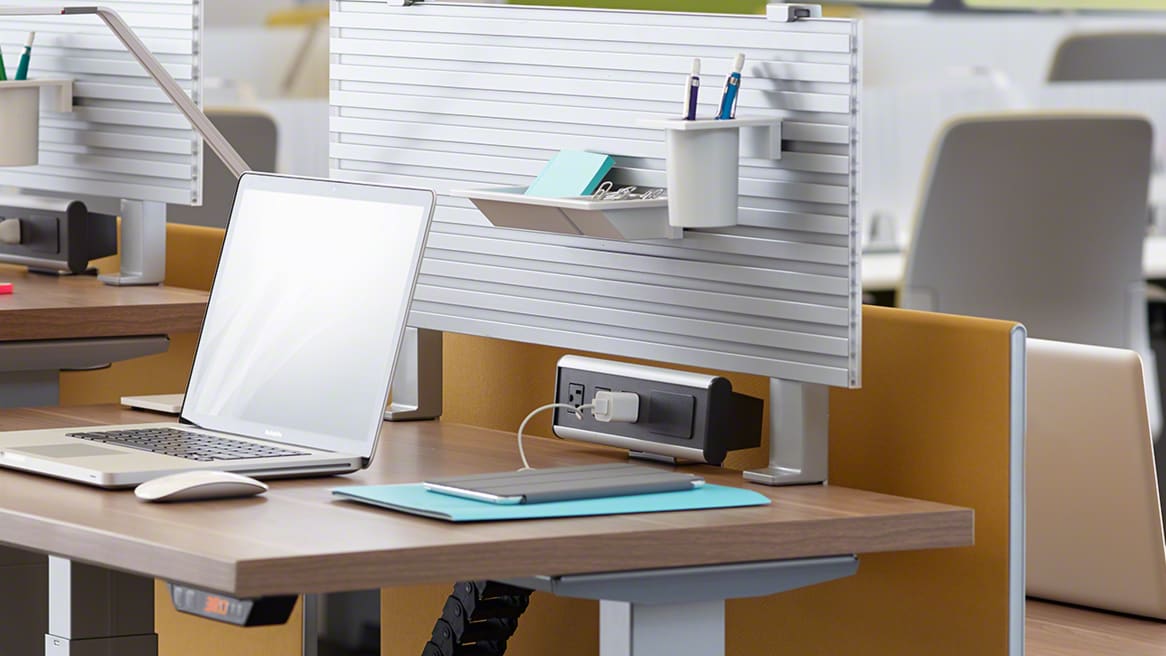 A laptop and other desk accessories are shown on a height-adjustable desk from Steelcase