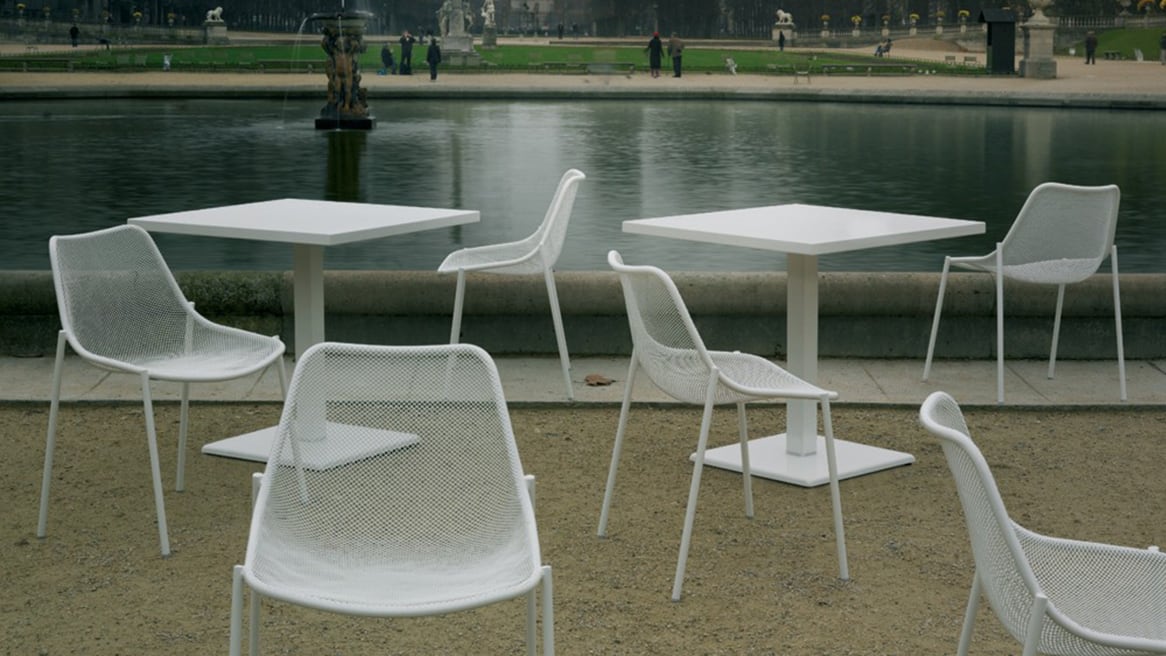 Two Emu Round Tables with Emu chairs in front of a fountain