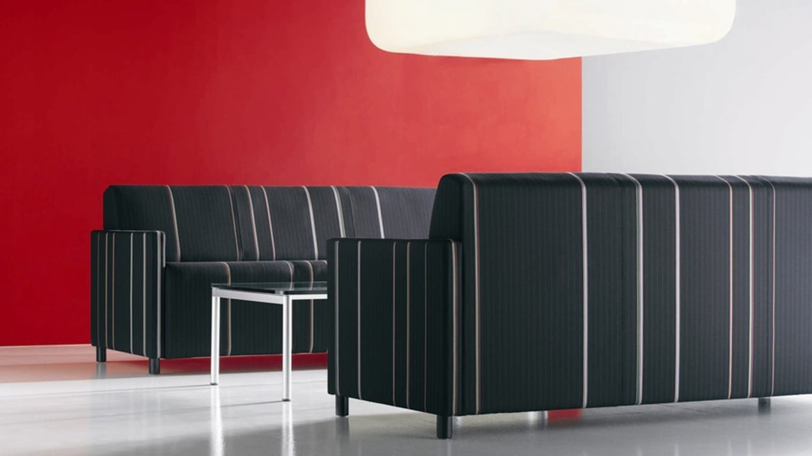 Two Black and White Striped Coupe Lounge Sofas facing each other in front of a red wall