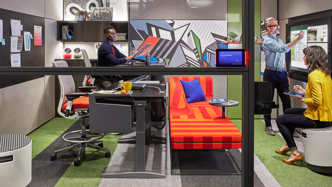 Three people work together in an office enclave furnished with Turnstone Buoy seating, Steelcase Think stools, and a Steelcase Ology bench Steelcase Room Wizard is seen next to the door
