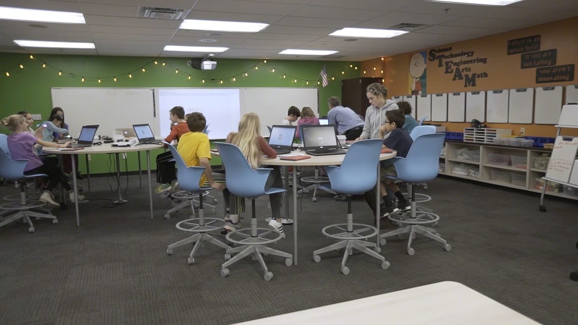 Kids in a classroom collaborating while seated on blue Node stools.