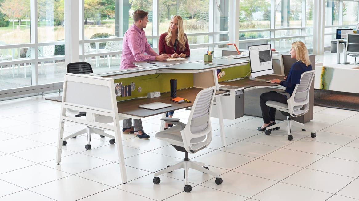 Three people work at workstations created using Bivi Dual Height desks and Steelcase Series 1 desk chairs