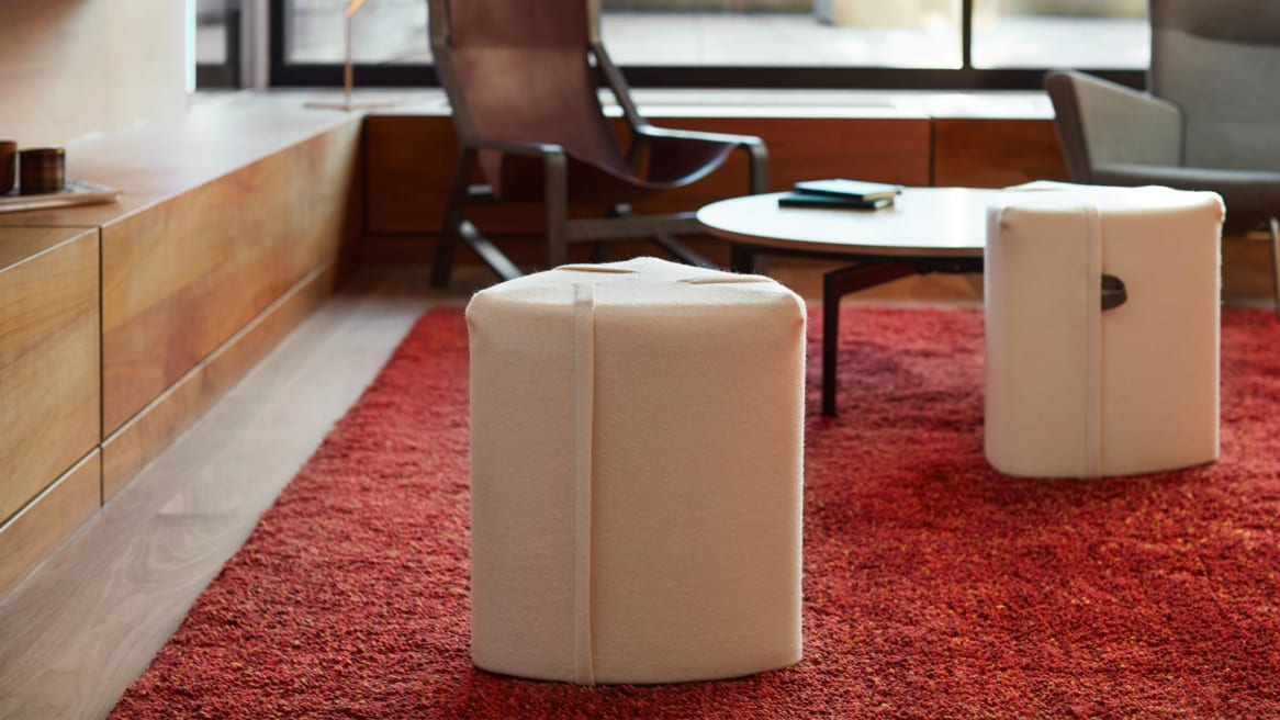Two taupe Campfire Poufs pictured with a Bassline table, CH445 Wing chair, and Blu Dot Toro lounge chair