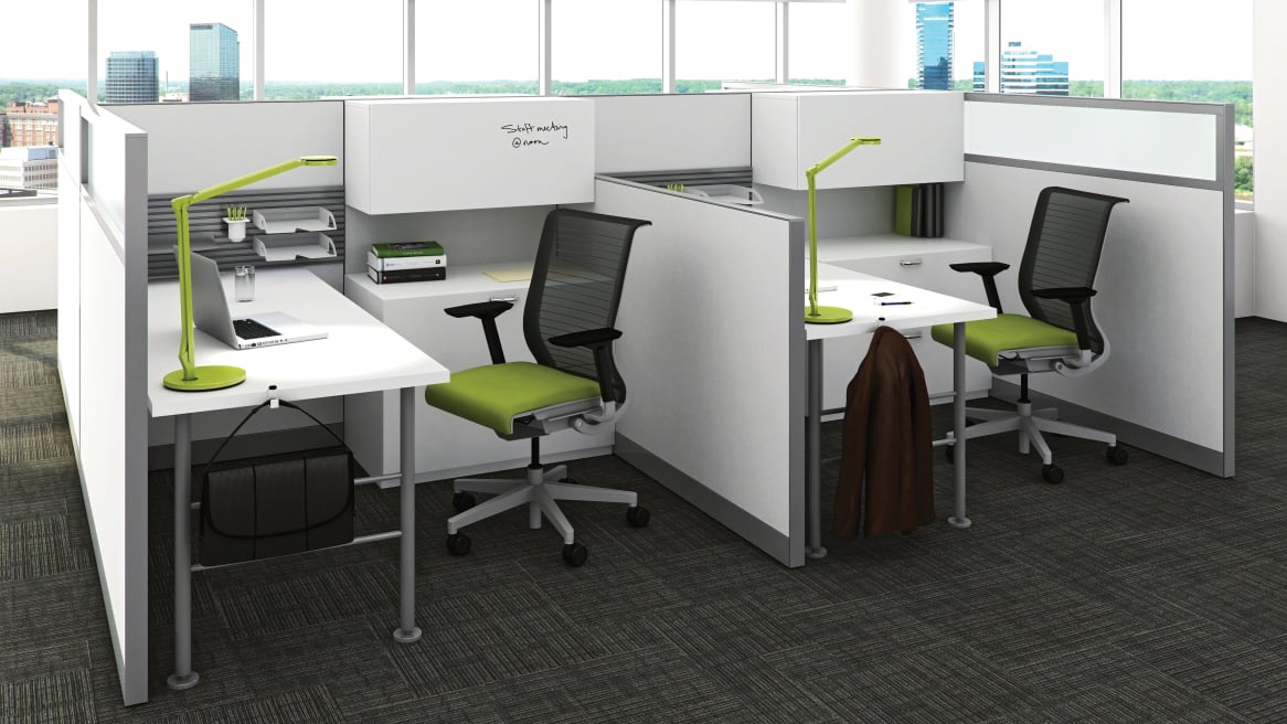 A Kick panel system is used to create two workstations, also featuring TS series storage and Think desk chairs with green upholstery from Steelcase