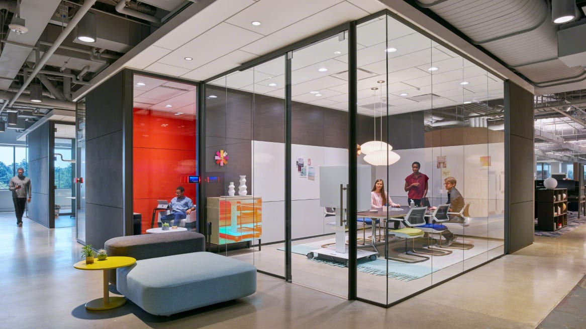 Three people use QiVi Collaborative chairs from Steelcase in a conference room with glass walls