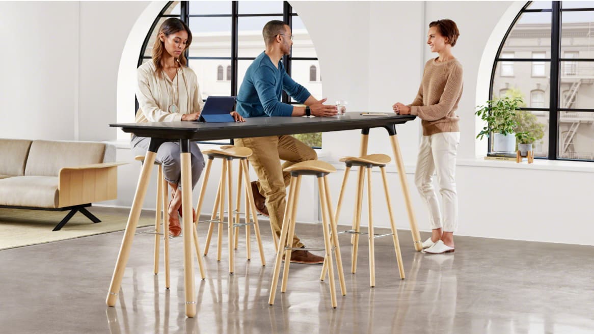 Three people gathered around a Potrero415 Light table with Enea cafe wood stools