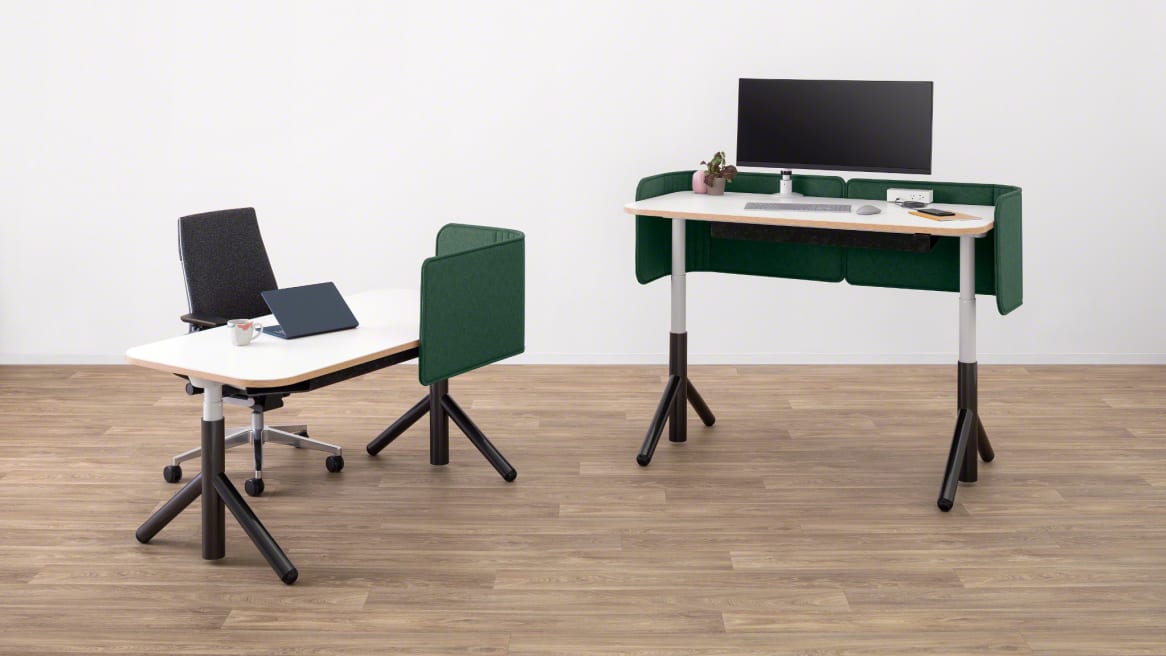 Two Steelcase Flex height-adjustable desks pictured with green privacy screens attached