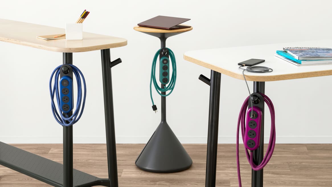 Steelcase Flex Power Hangers in various colors are seen hanging on a Steelcase Flex Stand, Flex Slim Table, and Flex Standing Height table