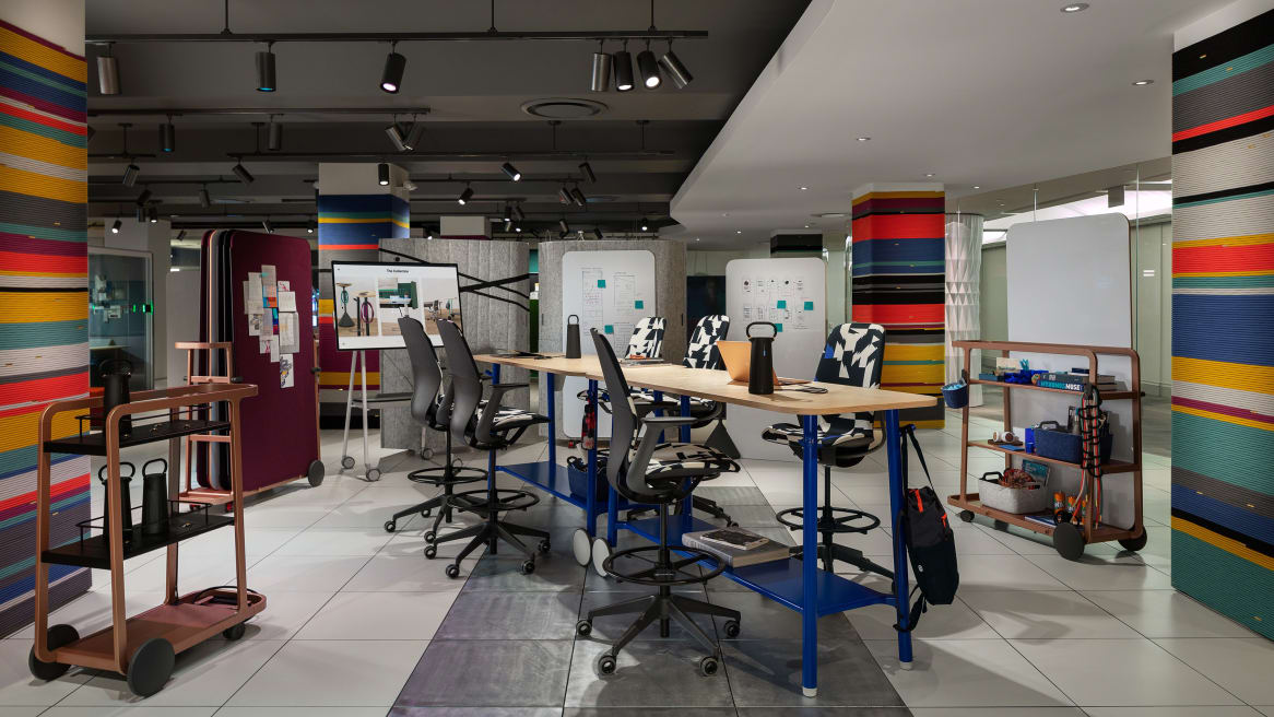 Products from the Steelcase Flex collection are displayed during NeoCon 2019, including Flex standing-height tables and Team Carts. SILQ stool height chairs are next to the tables.