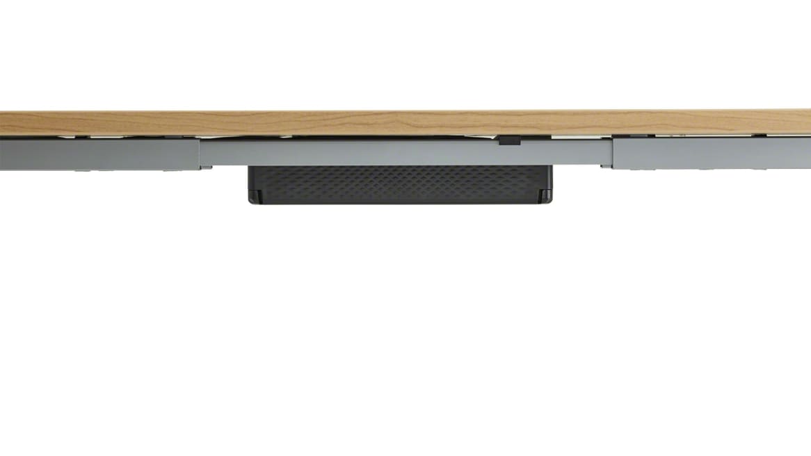 Black Steelcase Universal Cable Management Kit attached into a light wood desk.